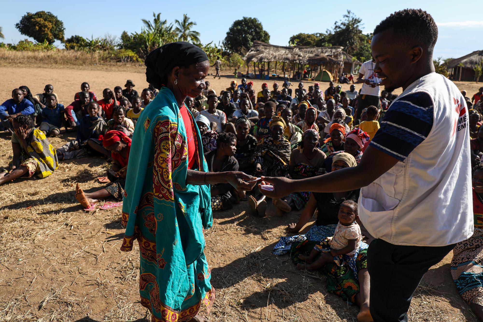 Agy Agy donne un ticket à une femme récemment déplacée our qu&#039;elle puisse récupérer un kit de secours, à Mumane, Montepuez. 