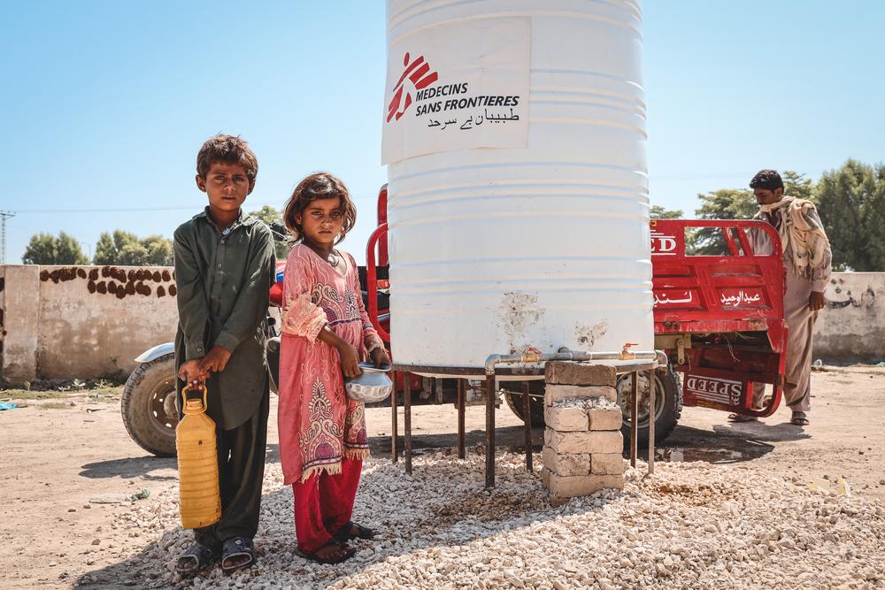 Des enfants collectent de l&#039;eau pour l&#039;apporter à leurs tentes, dans un camp de personnes déplacées, district de Dadu au Pakistan. 