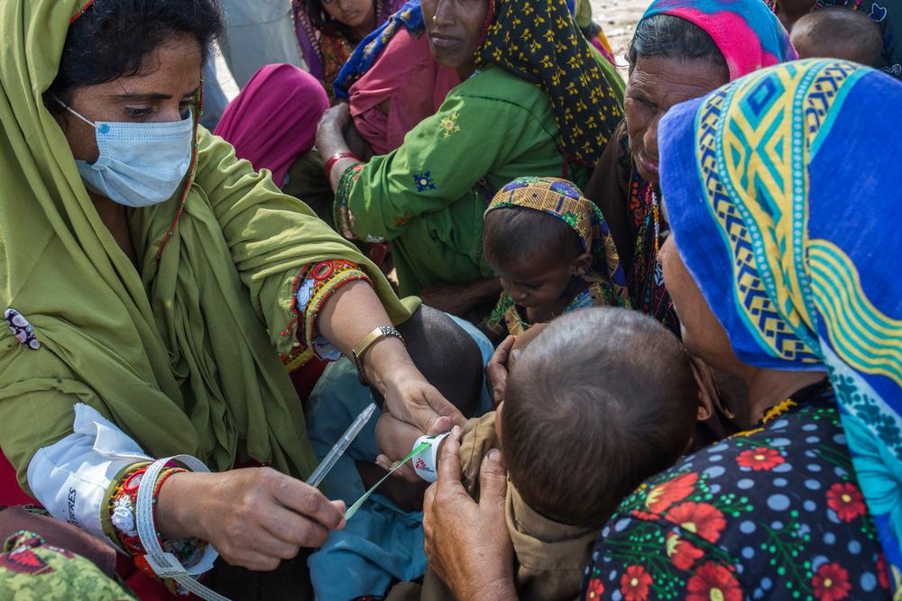 Sazia Bano, an MSF employee, examines a malnourished child during the setting up of a mobile clinic in Jacobabad district, Sindh province, Pakistan, October 26, 2022. 