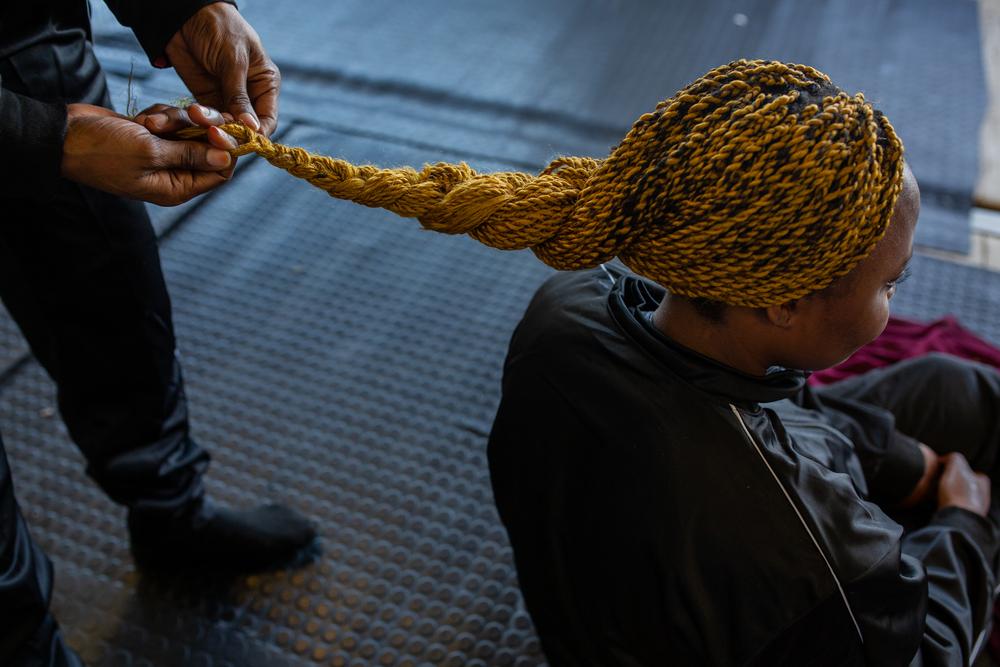Une femme tresse les cheveux de son amie, avec qui elle a fait le voyage depuis la Libye. 