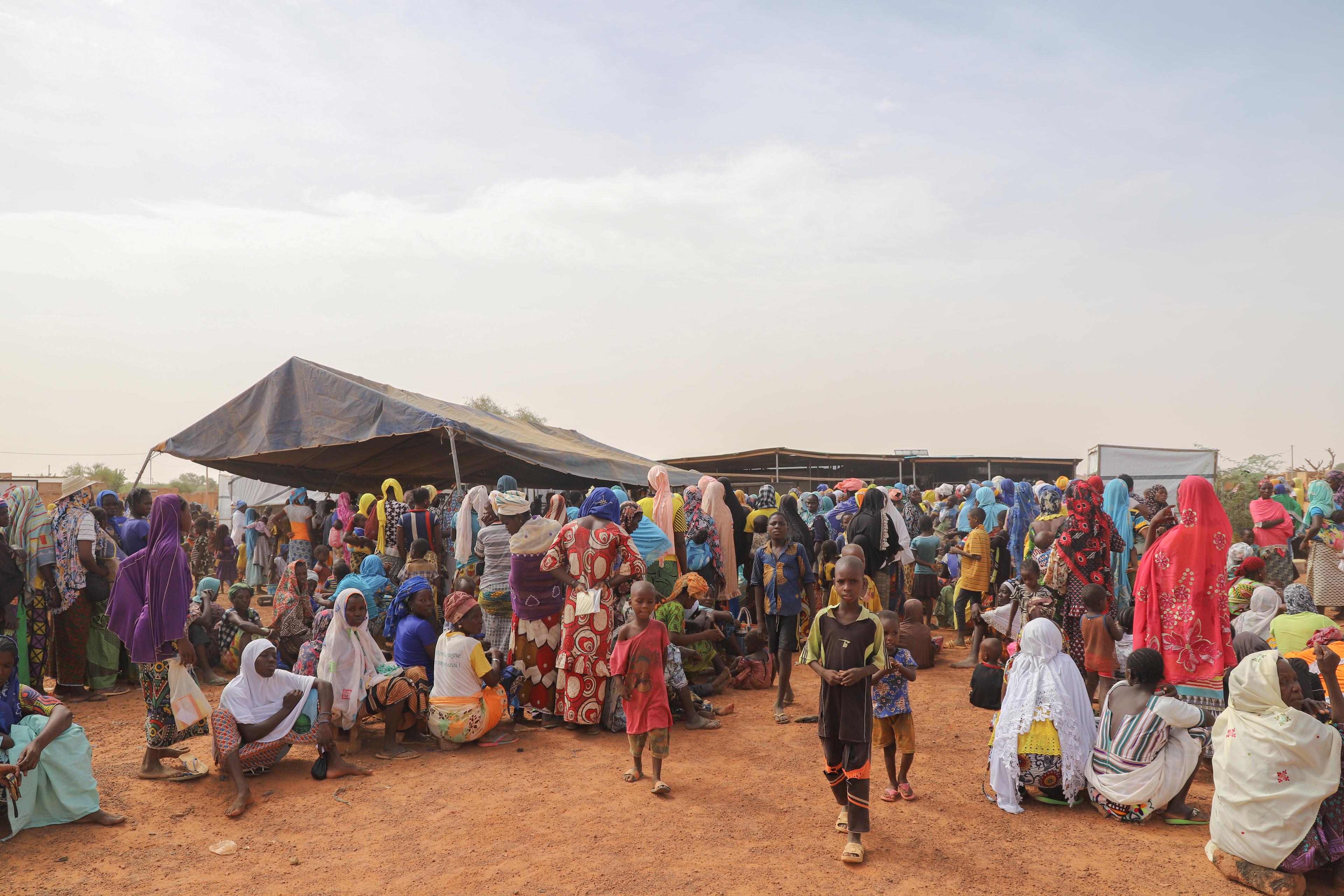 Des femmes et des enfants attendent sur le site de distribution. 