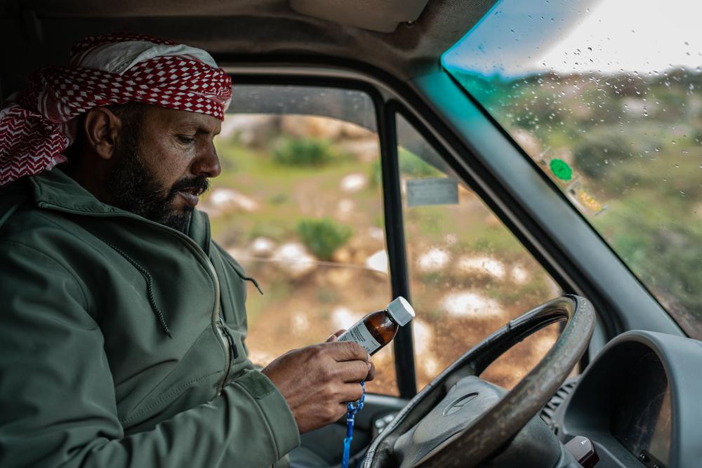 Mustafa Mlikat inspects a medicine bottle handed to him by his son in request to purchase a similar one for him, in Douma on 13 April 2023.. 