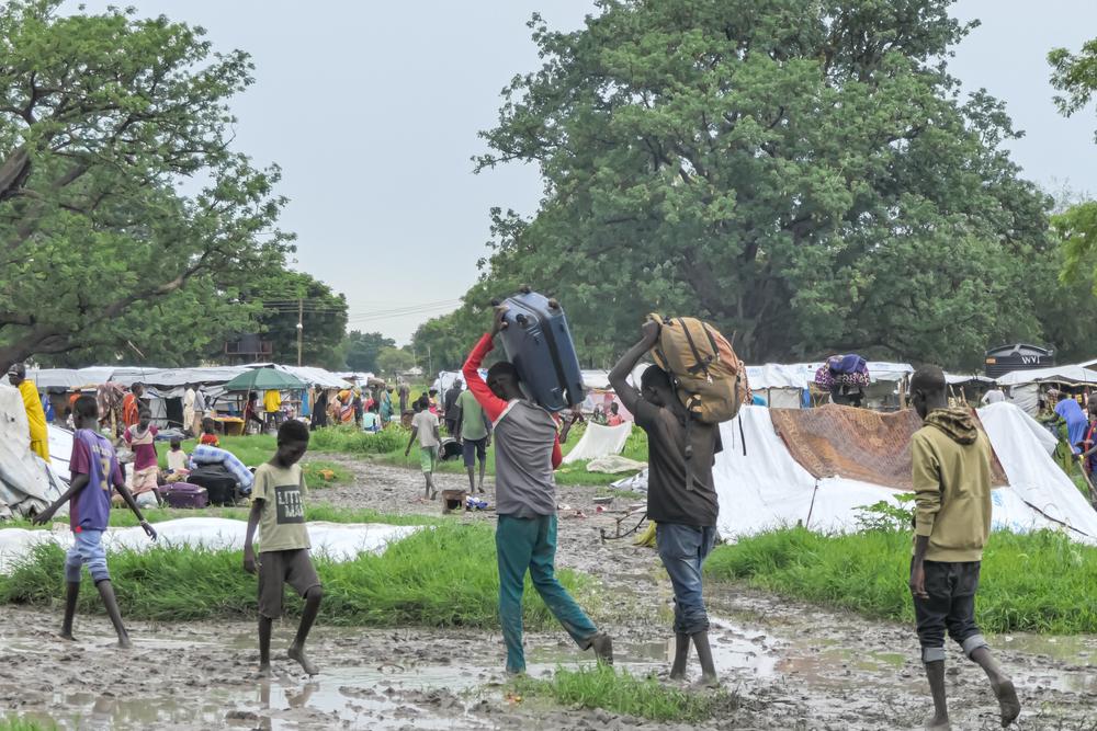 Des hommes, des femmes et des enfants nouvellement arrivés de Renk transportent leurs bagages vers les abris temporaires du camp de transit de Bulukat, dans l'État du Haut-Soudan, au Soudan du Sud.  Août 2023 