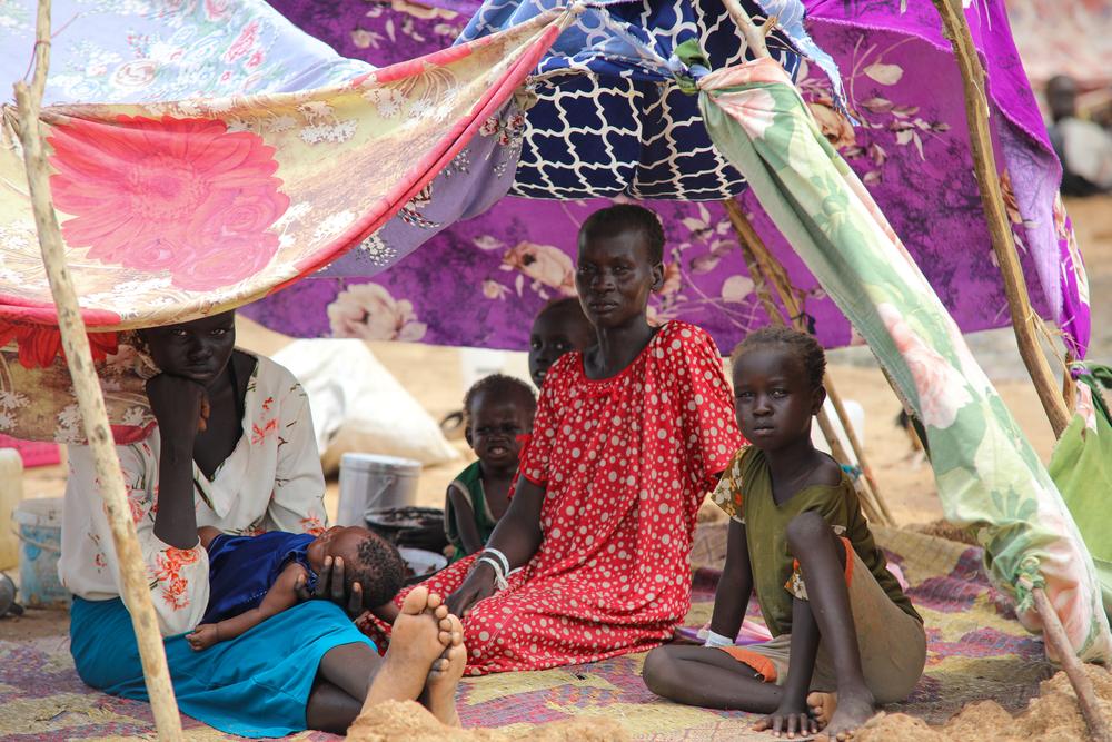 Nnyikang Both, a mother of 7, sits under their temporary shelter made from sheets and scraps of clothing at the Renk transit centre in Upper Nile State. 