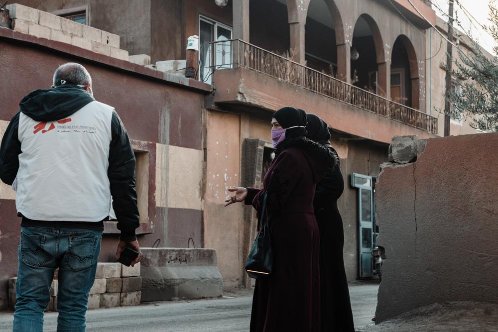 On the street in front of the MSF clinic in Arsal, a staff member talks with two patients. December 2020. 
