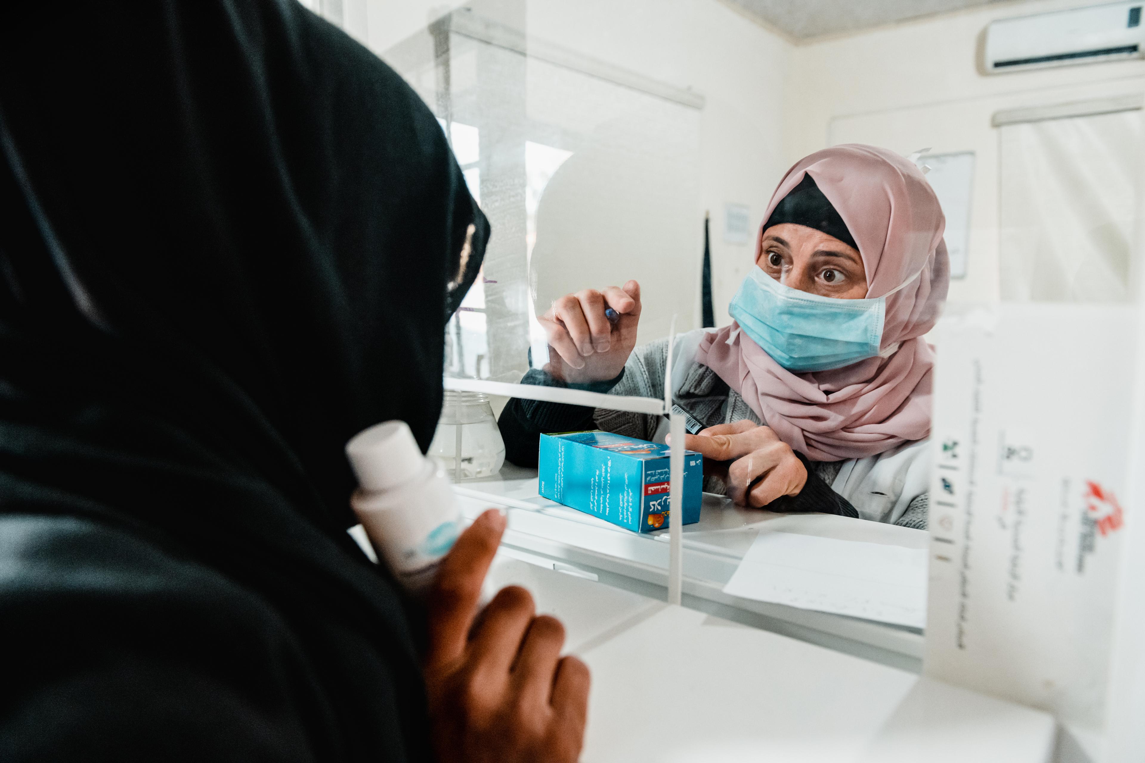 Après sa consultation médicale, une femme récupère ses médicaments. Décembre 2020. 