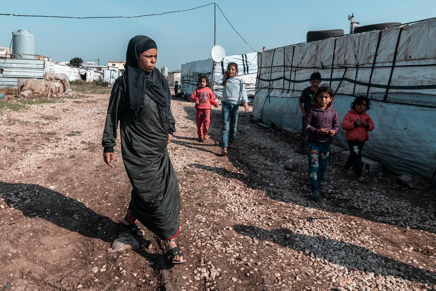 Samaher, a 40-year-old Syrian refugee, walks in the informal tented settlement in Akkar, north Lebanon, where she lives with her husband and her four children. Lebanon, December 2020. Karine Pierre/Hans Lucas for MSF