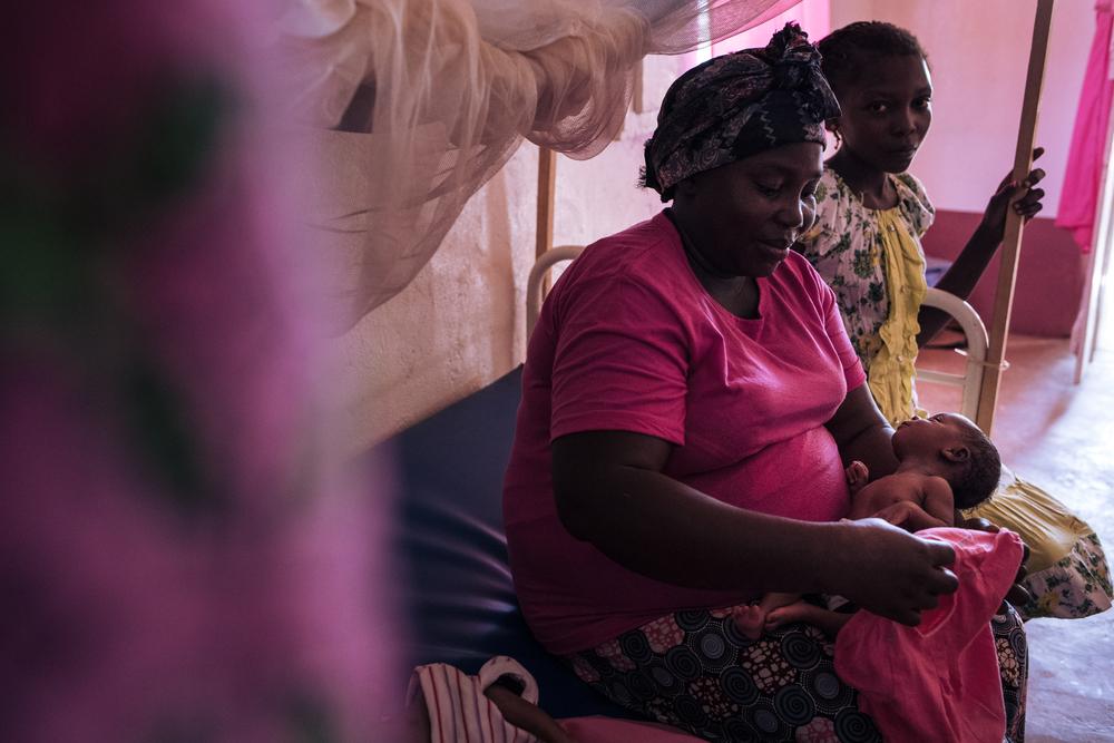 Ester (en rose) et sa fille aînée Princia (en jaune) tiennent dans leurs bras les jumeaux Laure et Rhode, avant leur consultation, le 27 janvier 2021.