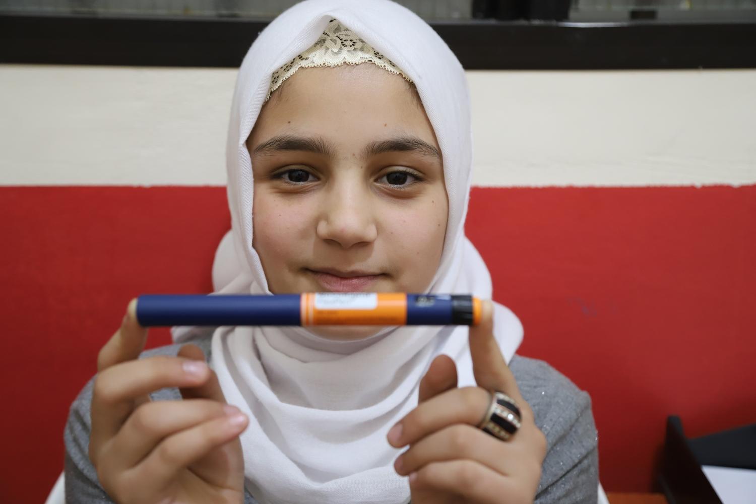 Sidra, a 12-year-old patient with type 1 diabetes, holds her insulin pen. Shatila camp, south Beirut, Lebanon. 2019. 
