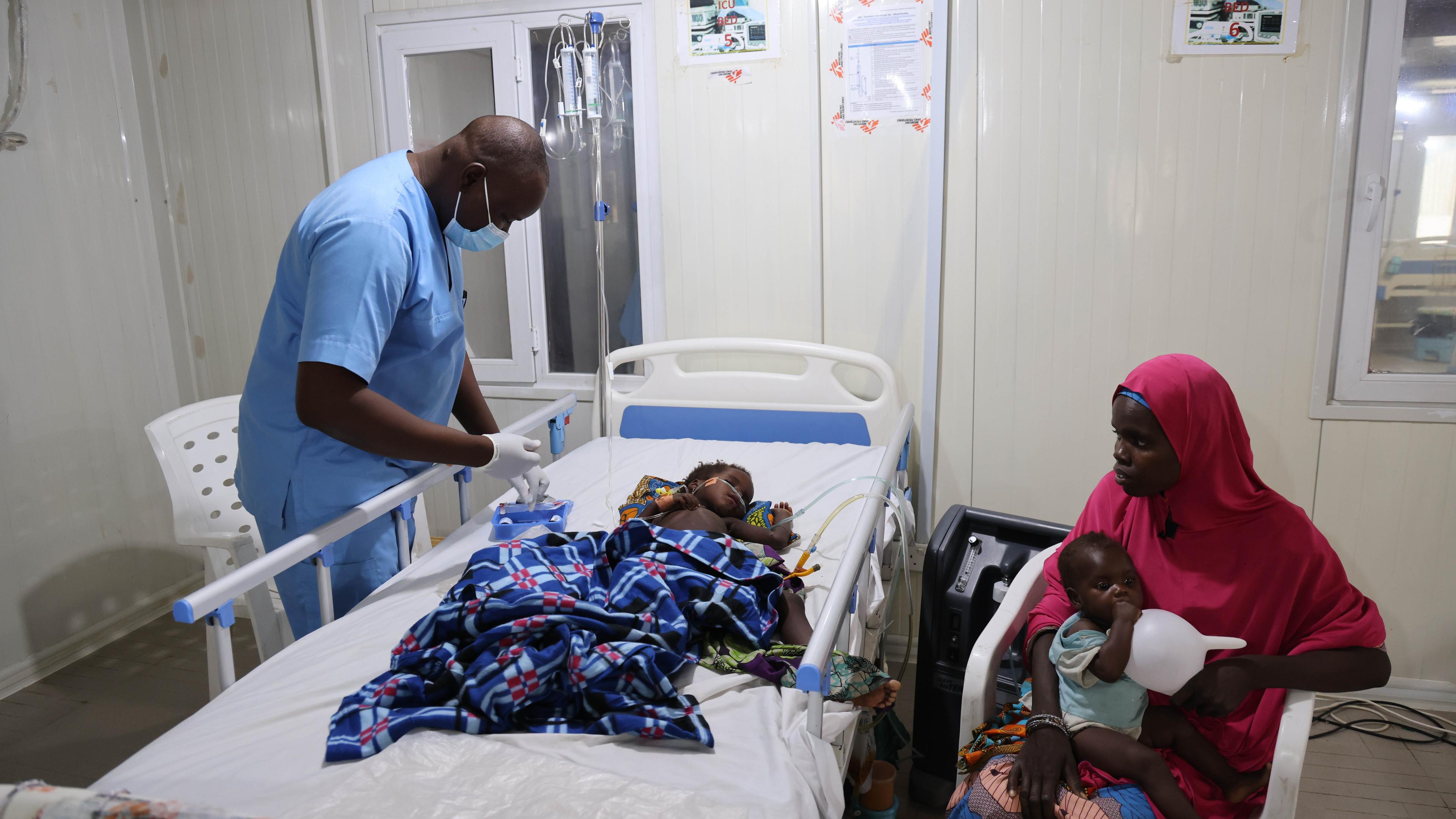 An MSF nurse cares for a seriously ill child admitted to the emergency room in Nilefa Kiji while his mother looks on. 