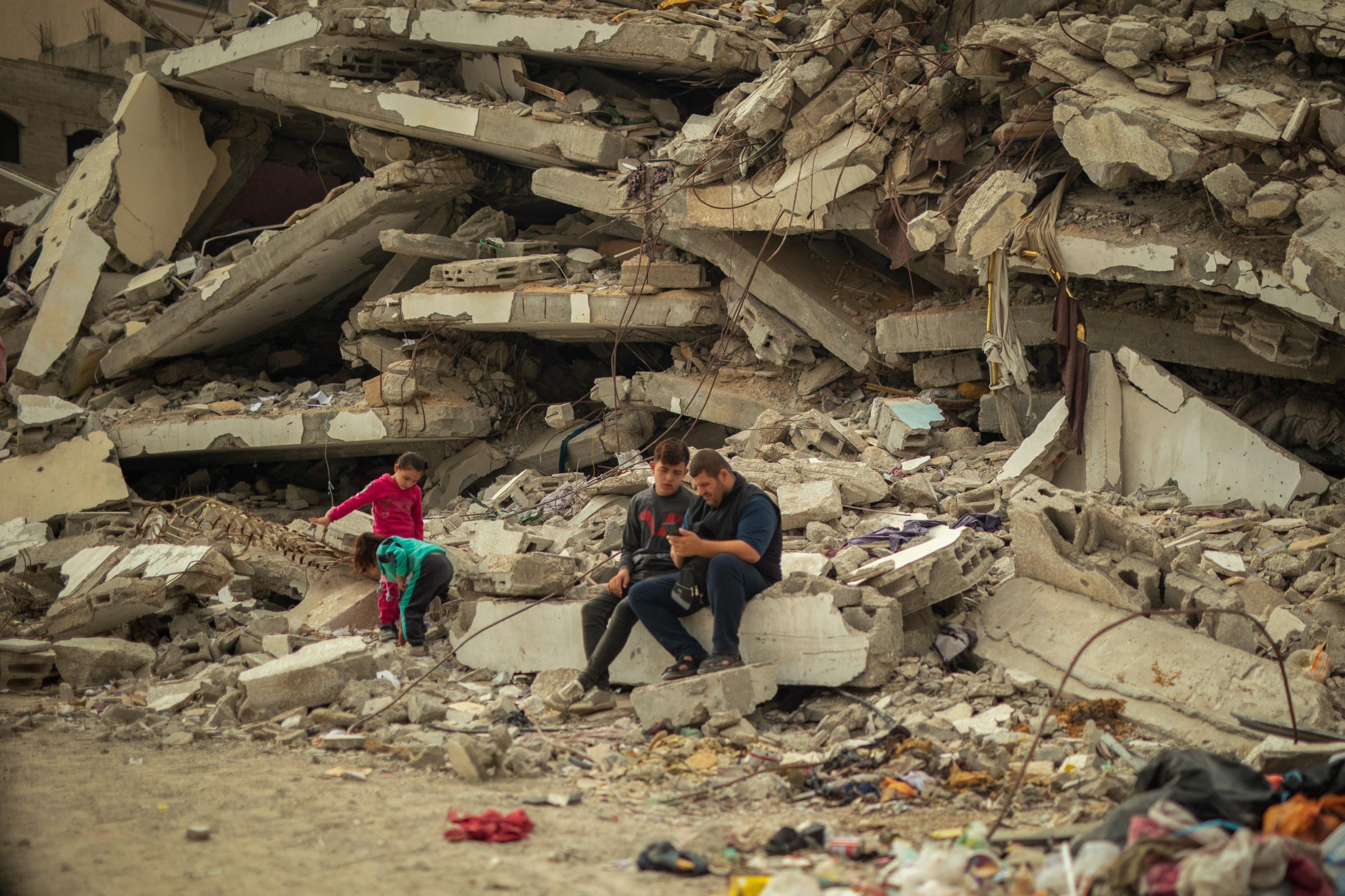 À Al Saraya, dans la ville de Gaza, les gens sont assis sur les décombres de leur maison détruite, avec leur tente installée en face des débris.