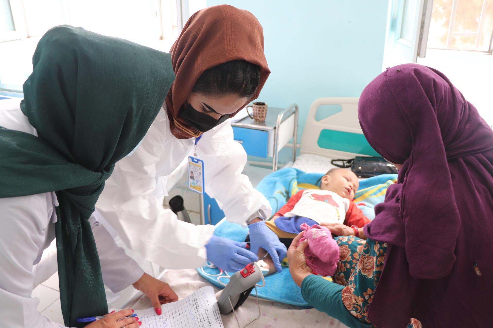 Farida, une infirmière de MSF, vérifie les signes vitaux d'Ali Ramin, un bébé de 10 mois, dans le service d'isolement de la rougeole à l'hôpital régional de Mazâr-e Charîf, dans la province de Balkh. © Tasal Khogyani/MSF