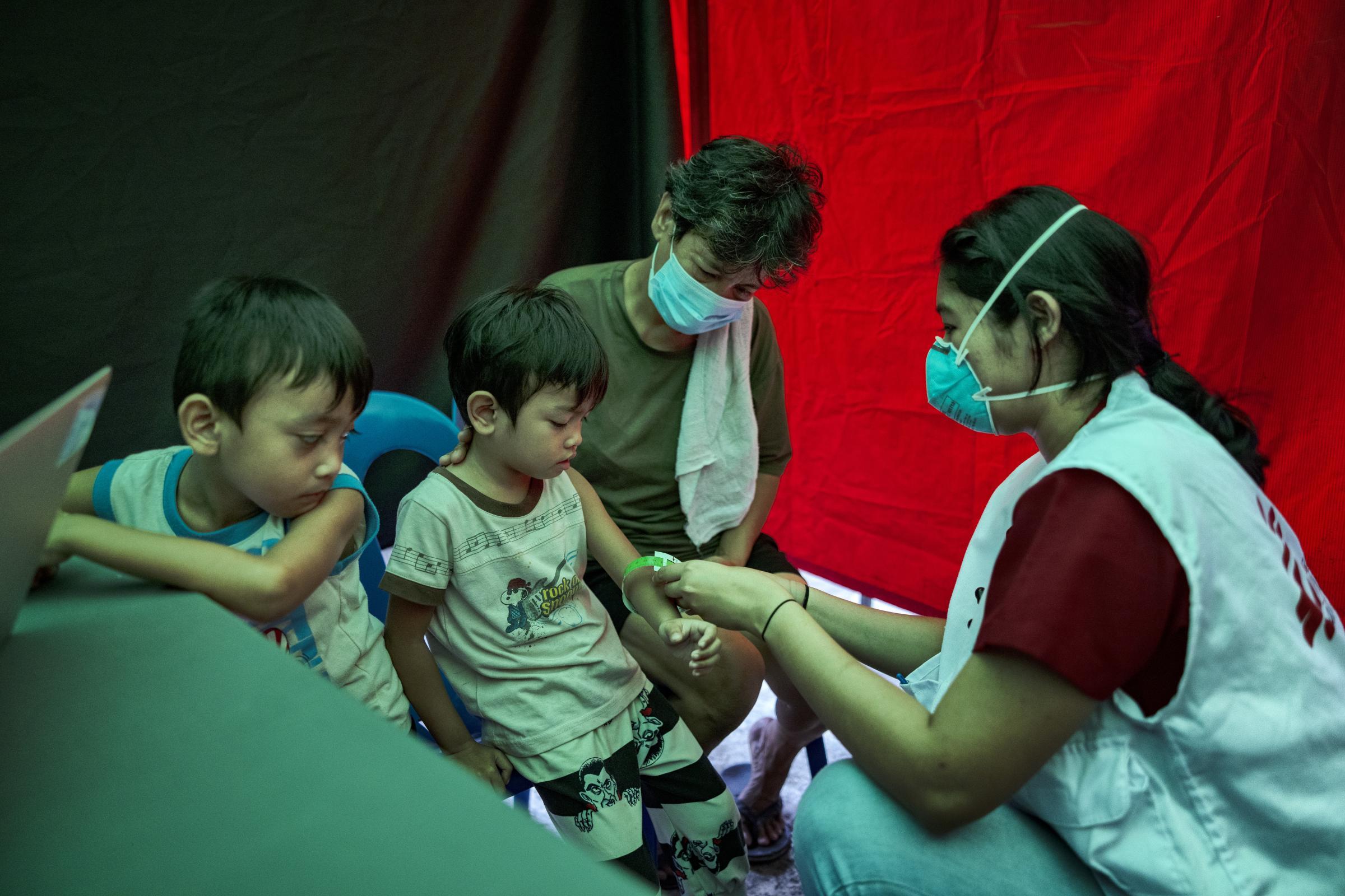 Agustina et son petit-fils Clark regardent Trisha Thadhani, médecin spécialiste de la tuberculose chez MSF, procéder à une évaluation médicale de son autre petit-fils.