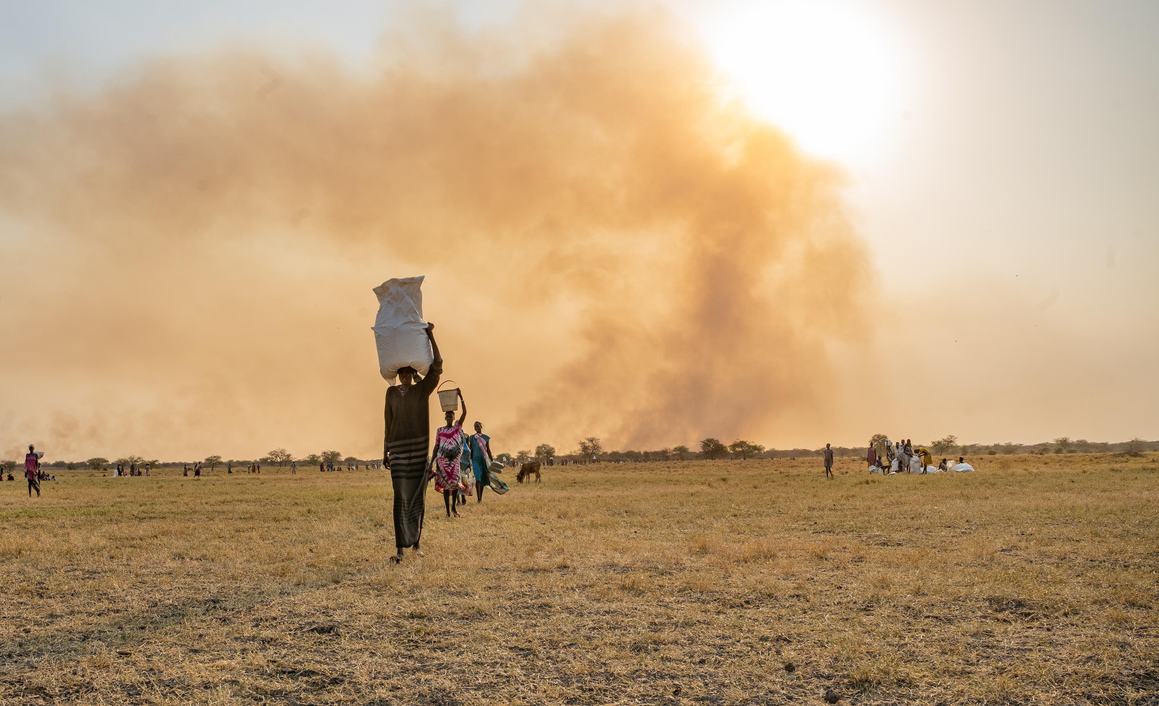 Une femme transporte des sacs de nourriture sur la tête après un largage de vivres effectué par le Programme alimentaire mondial près de Chuil.