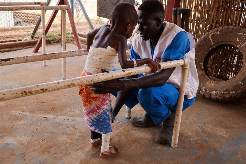 Un kinésithérapeute de MSF aide un jeune patient victime de brûlures à remarcher.