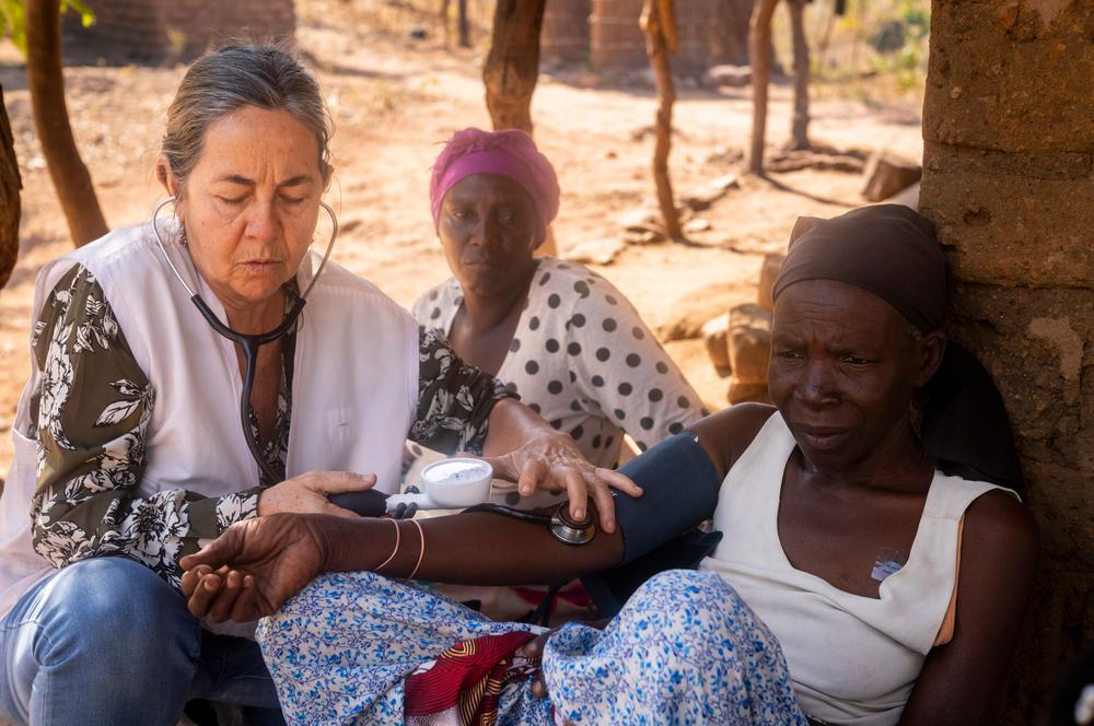 Un membre de l'équipe de soins palliatifs de MSF prend la tension artérielle d'Aida Mailosi, 66 ans, sous le regard de sa fille et soignante, Rose Naisoni, à Lirangwe, dans le district de Blantyre, au Malawi. Malade depuis huit ans, Aida ne pouvait plus marcher à cause de ses plaies, alors l'équipe a commencé à venir chez elle une fois par mois. Juillet 2026 © Jérémy Lempin