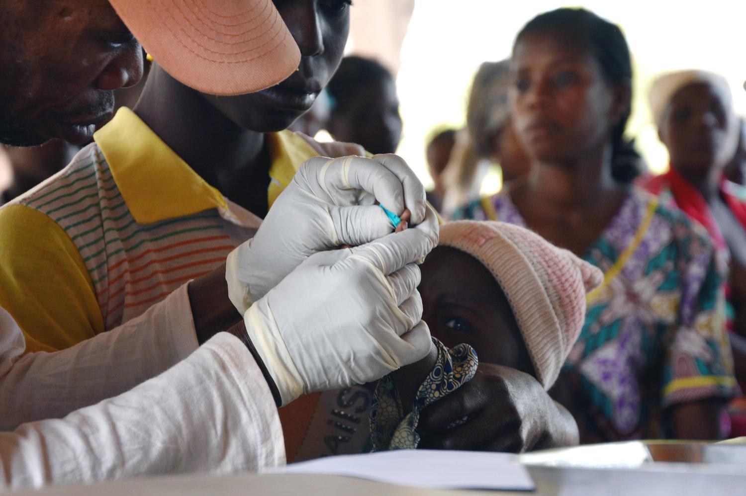 Ten-month-old girl is pricked on the finger for a rapid test to detect malaria at a health facility in Boguila. Central African Republic, February 2019.  