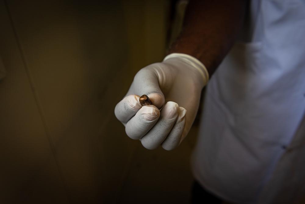 An MSF staff physician shows a projectile extracted from a patient who was shot in his neighbourhood. Stray bullets, mostly large caliber, are becoming a growing problem in Port-au-Prince. Haiti, June 2022. 