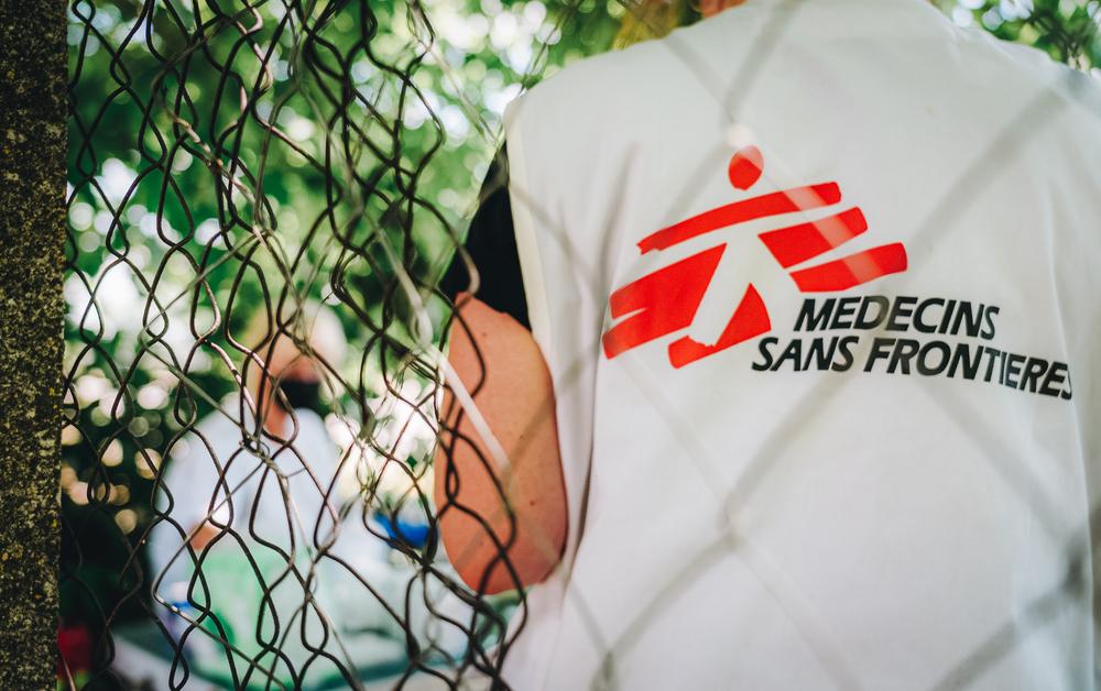 Un travailleur de MSF se tient près d'une clôture de barbelés pendant une consultation médicale de la clinique mobile de MSF dans la zone frontalière de Horgos 2 en Serbie. 