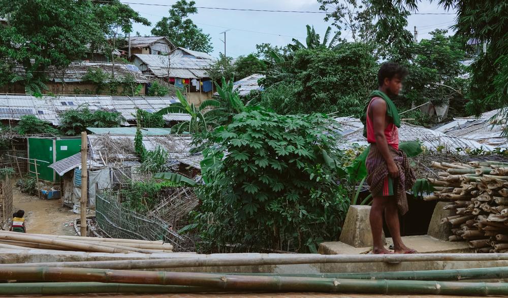 A Rohingya person helping unload bamboo. The bamboo and tarpaulin shelters were built as temporary solutions. Many Rohingya families fled Myanmar thinking they would return to their homes within a few months. 