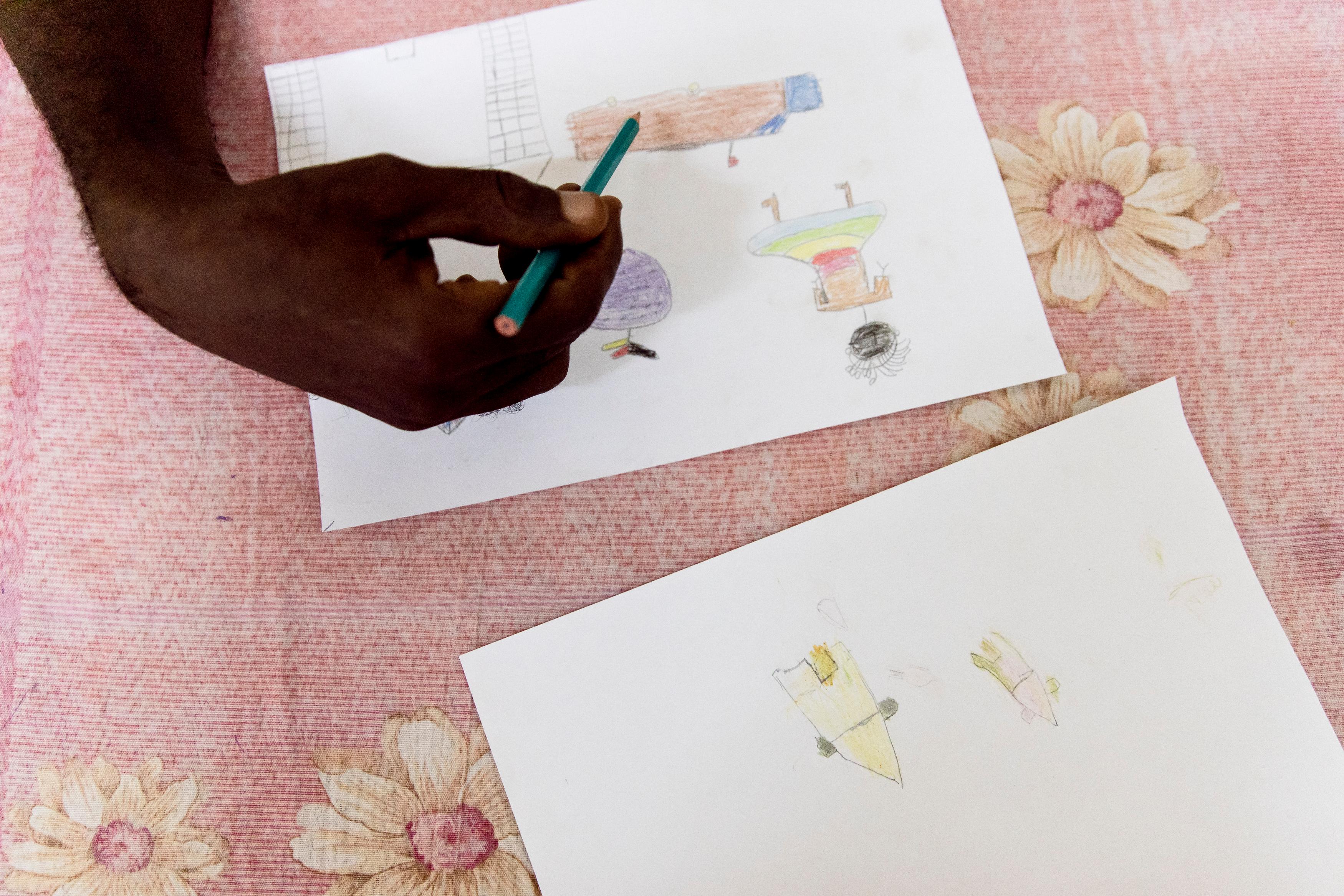 imé Césaire Likosso, mental health advisor with the MSF Tongolo project in Bangui, CAR, points out details in drawings made by child sexual assault survivors. Tongolo. November 2020. 