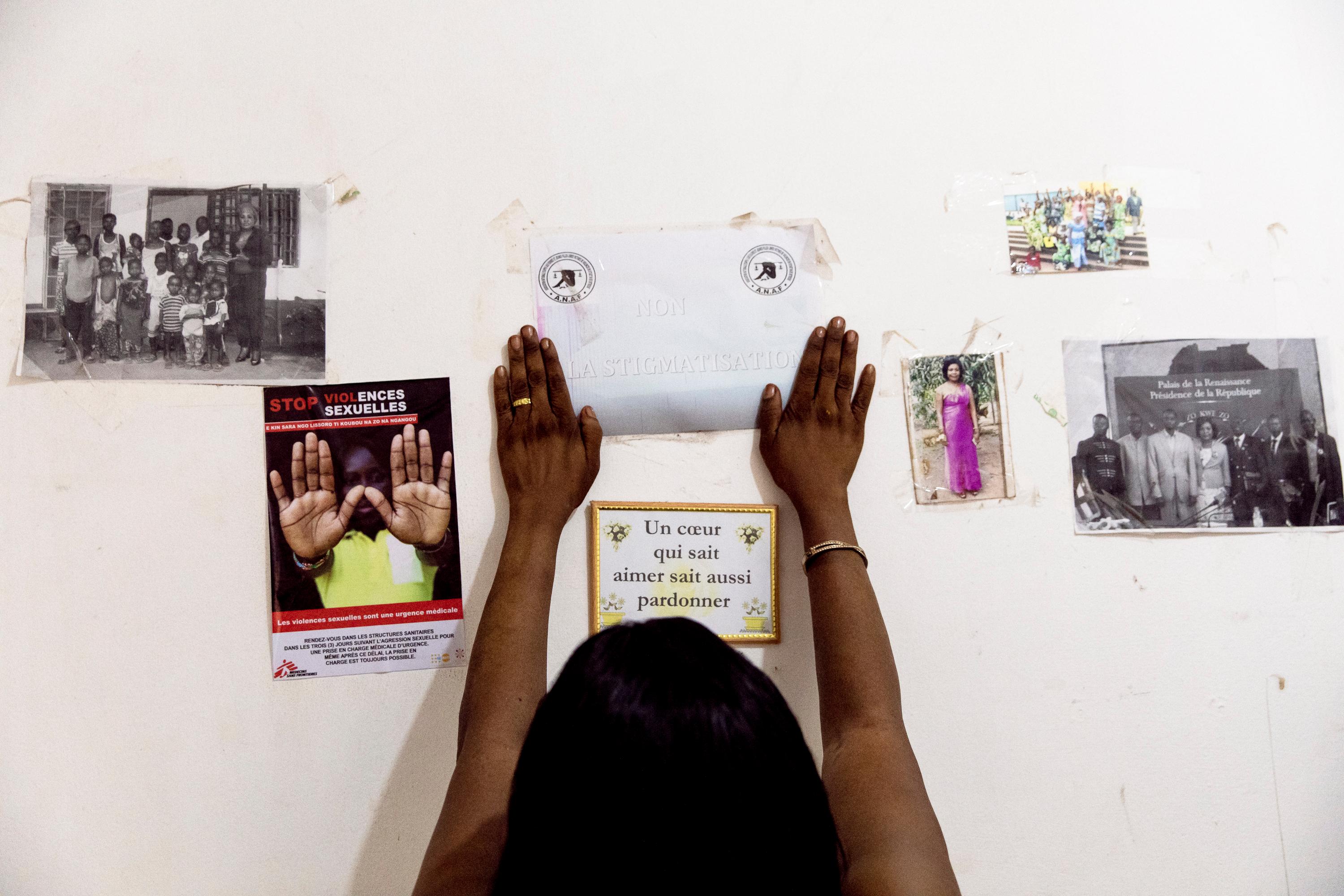 Nanette fixes a poster that says &quot;no to stigmatizsation&quot; in her office in Bangui, the Central African Republic. Tongolo. December 2020. 