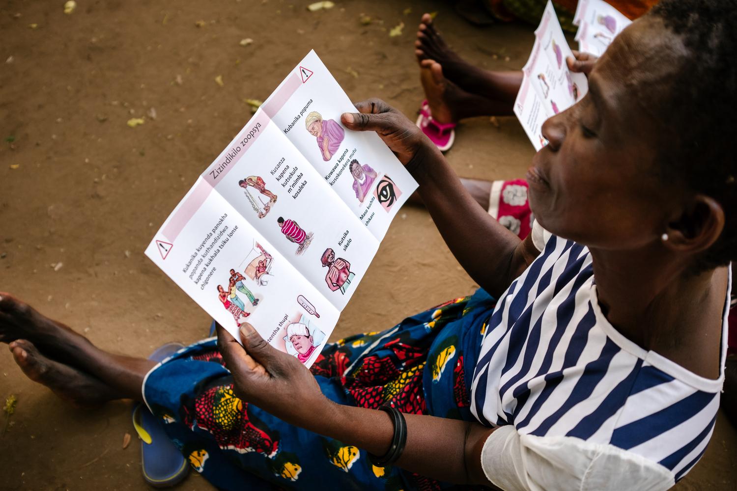 Un membre d&#039;un groupe de soutien lisant une brochure de sensibilisation au VIH axée sur les signes de danger au centre de santé de Ndamera, dans le district de Nsanje. Malawi, octobre 2019.