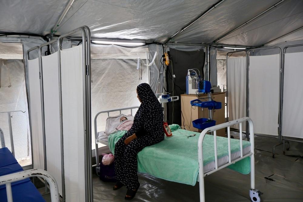 Faten, une mère de 39 ans, se tient debout à côté de son petit garçon qui souffre d’une grave infection respiratoire