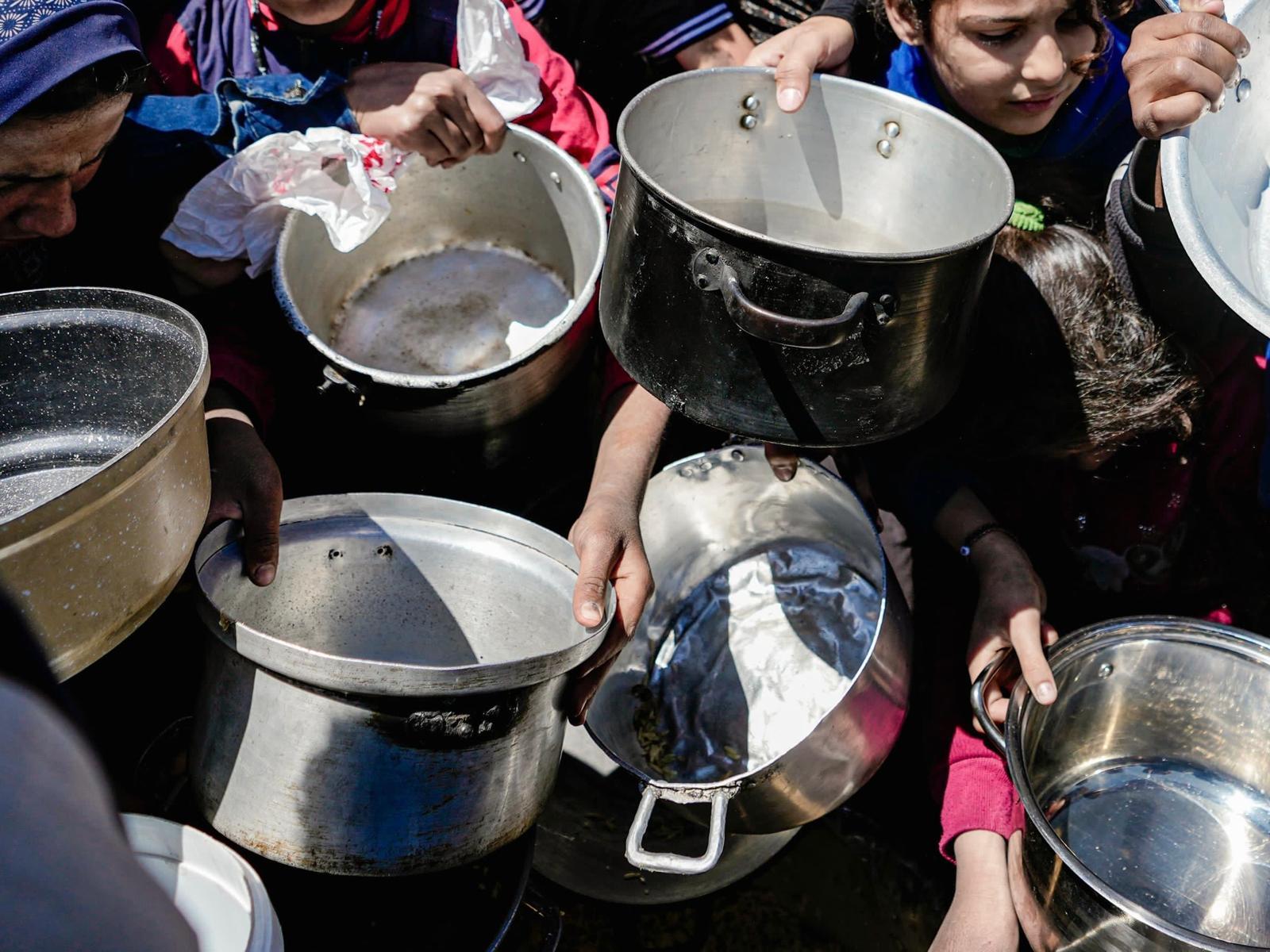 Des enfants tenant leurs pots vides dans une cuisine communautaire du nord de Gaza.