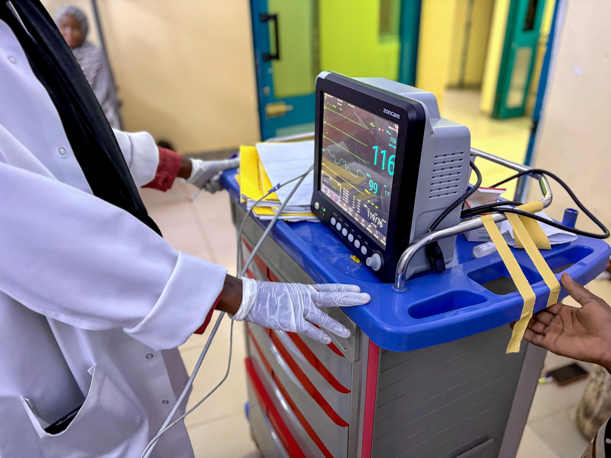 Dans le service de maternité de l'hôpital, un membre du personnel médical surveille l'écran du moniteur tout en vérifiant les signes vitaux d'une patiente à l'Hôpital Universitaire Bashair, Soudan
