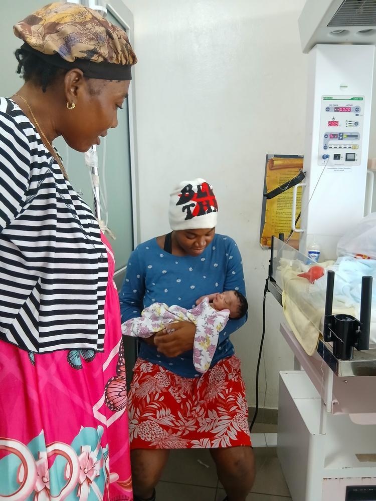 Après plusieurs jours de séparation dus à la violence armée, Sterline serre à nouveau sa fille nouveau-née dans ses bras à Cité Soleil, à Port-au-Prince, en Haïti. Sa mère se tient à ses côtés, rassurée.