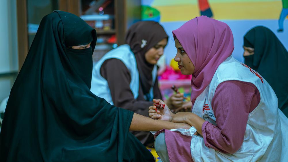 Au sein du service de santé mentale de MSF de l’hôpital de Kutupalong, Fatema Jinnat Laboni, assistante sociale, et Rozina Akter, formatrice en psychologie, animent une séance de soutien psychosocial. À travers des activités telles que l’application de henné, l’équipe crée une ambiance décontractée qui leur permet d’instaurer un climat de confiance, d’écouter les témoignages des patients et de mieux cerner leurs besoins psychosociaux. Bangladesh, août, 2026 © Nazmul Islam/MSF