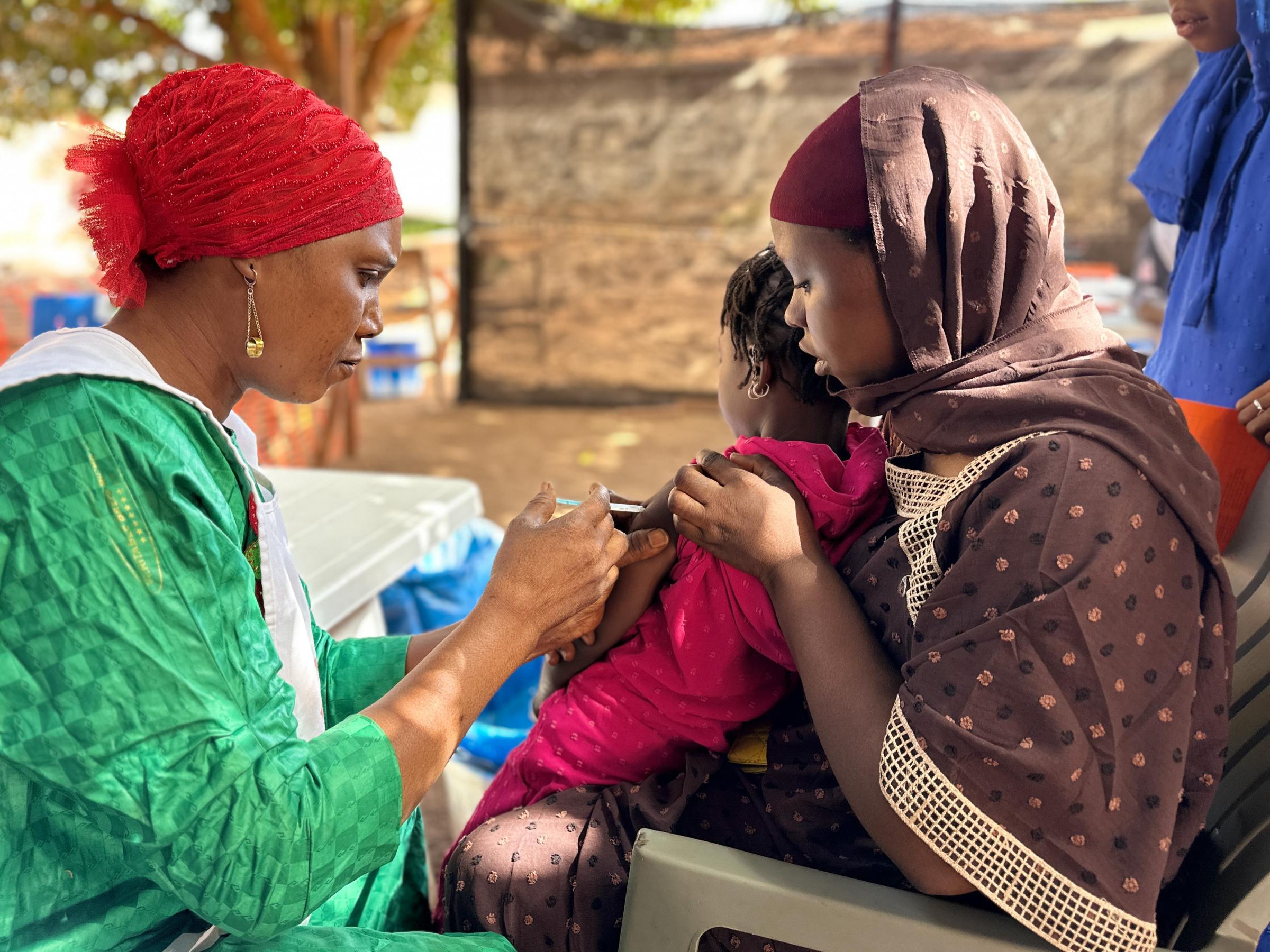 Diaka Kaba, membre de l’équipe de Médecins Sans Frontières, administre un vaccin contre la diphtérie à une enfant dans le quartier Hèrèmakonön, à Siguiri, en Guinée.