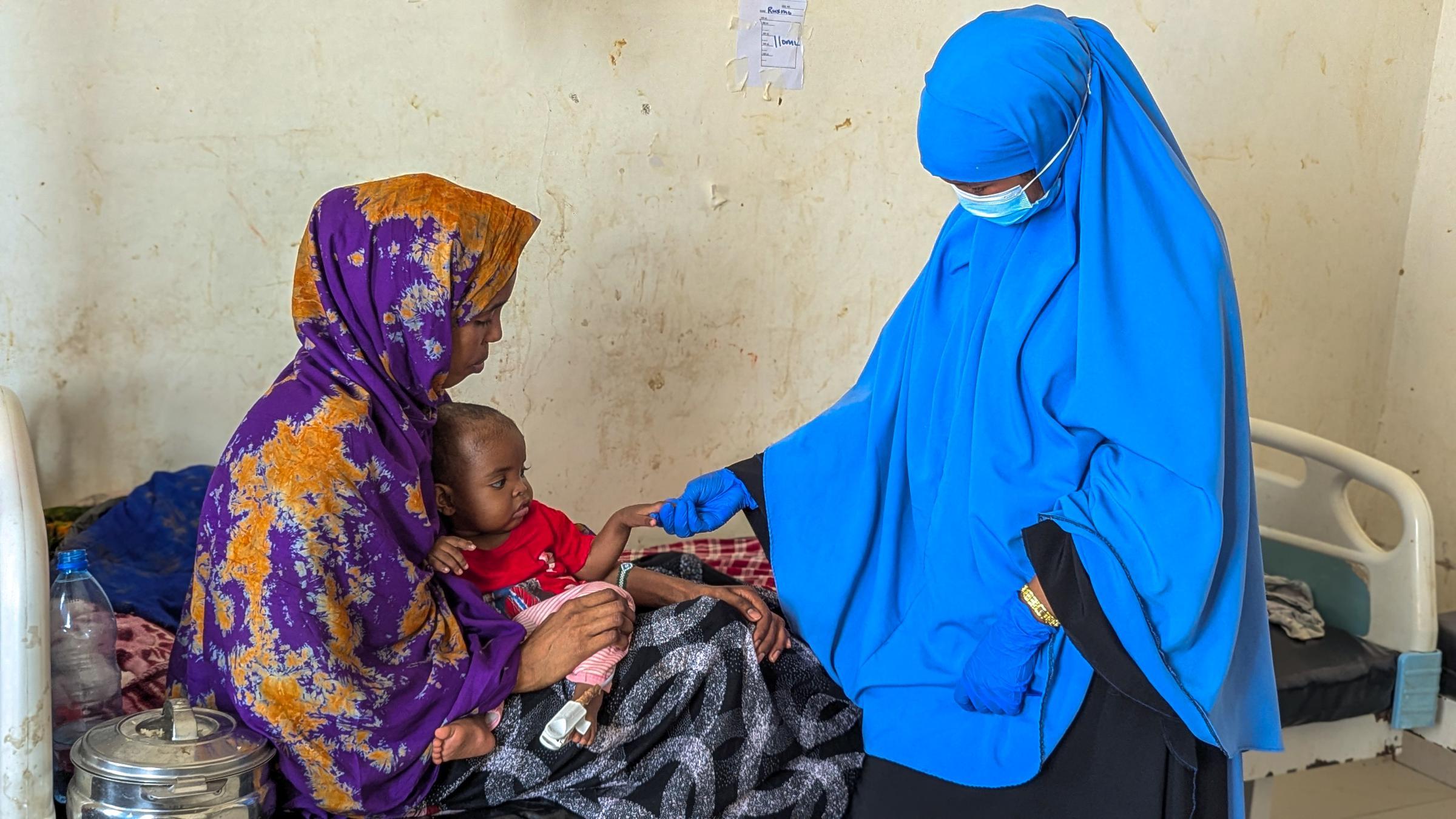 Une mère et sa fille avec un membre du personnel de santé à l'hôpital régional de Mudug, Somalie