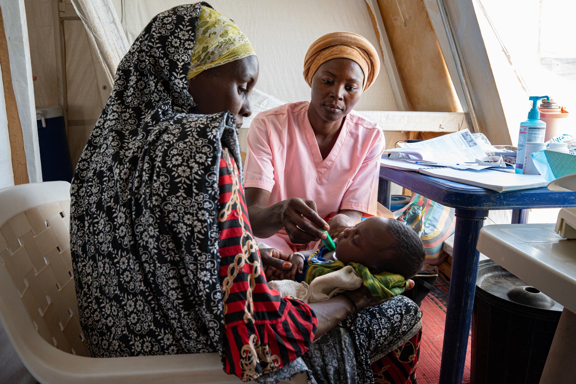 Une sage-femme examine un bébé en présence de sa mère