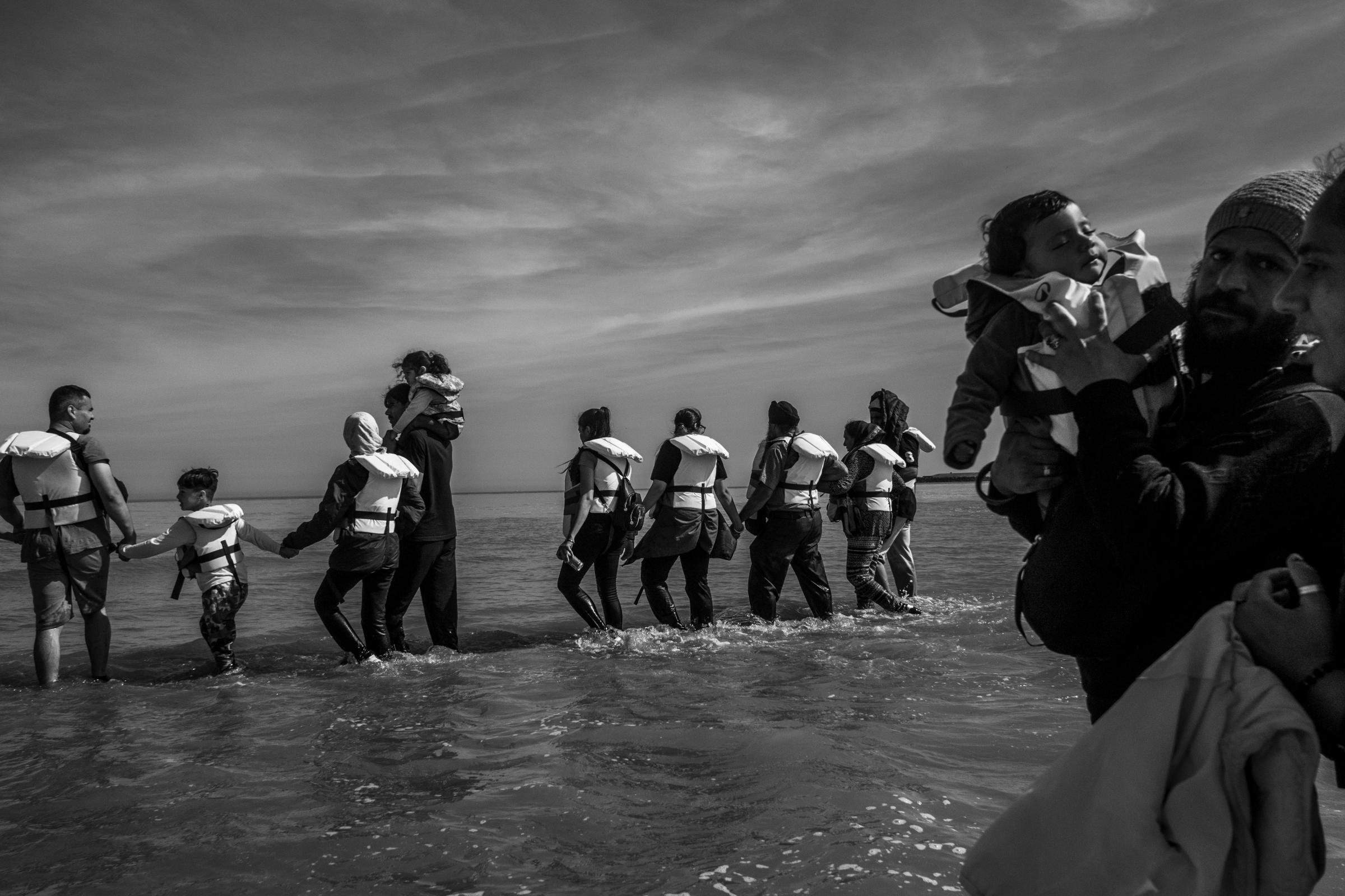 Un groupe d'exilés patauge dans l'eau pour rejoindre un bateau pneumatique dans une tentative de traversée de la Manche, à Grand-Fort-Philippe, en France.