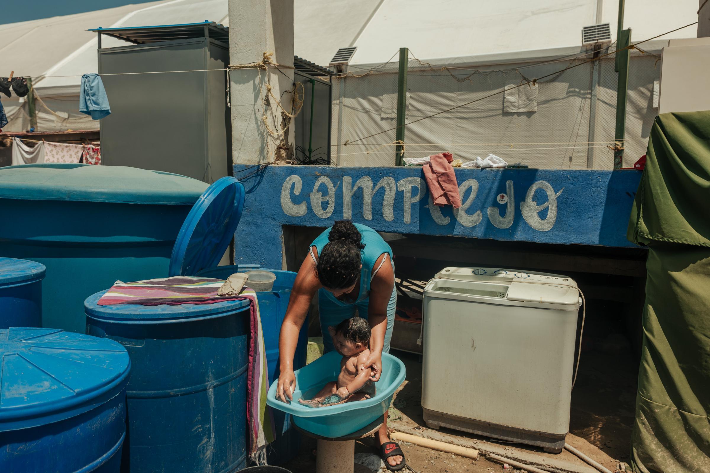 Greydiel Álvarez, 22 ans, donne le bain à son fils Kleiber Capote, âgé de 3 mois. La famille vit dans un campement temporaire installé à l'extérieur de Mare Abajo, un complexe résidentiel qui s'est partiellement effondré lors des deux séismes au Venezuela