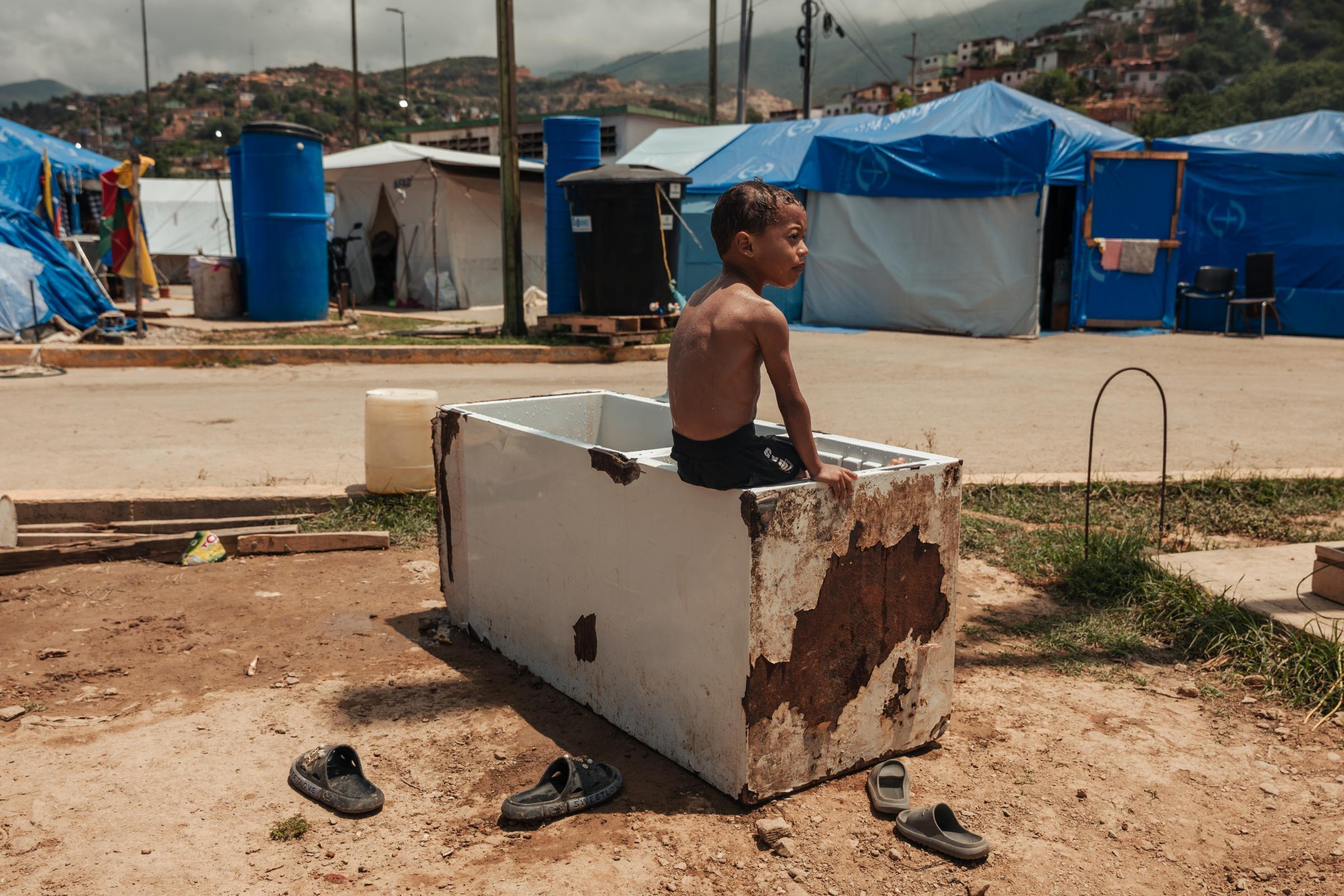 Deiberson Torres, 7 ans, joue dans un réfrigérateur hors d'usage que des familles ont transformé en piscine improvisée pour aider les enfants à supporter la chaleur extrême d'un campement installé à proximité d'un complexe résidentiel à Brisas de Maiquetía, au Venezuela